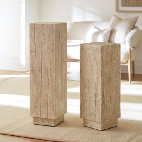 two wooden vases sitting on top of a rug in front of a white couch