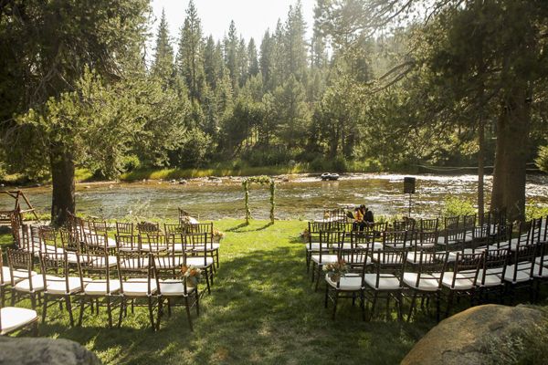 an outdoor ceremony set up with chairs and trees in the background, surrounded by large rocks