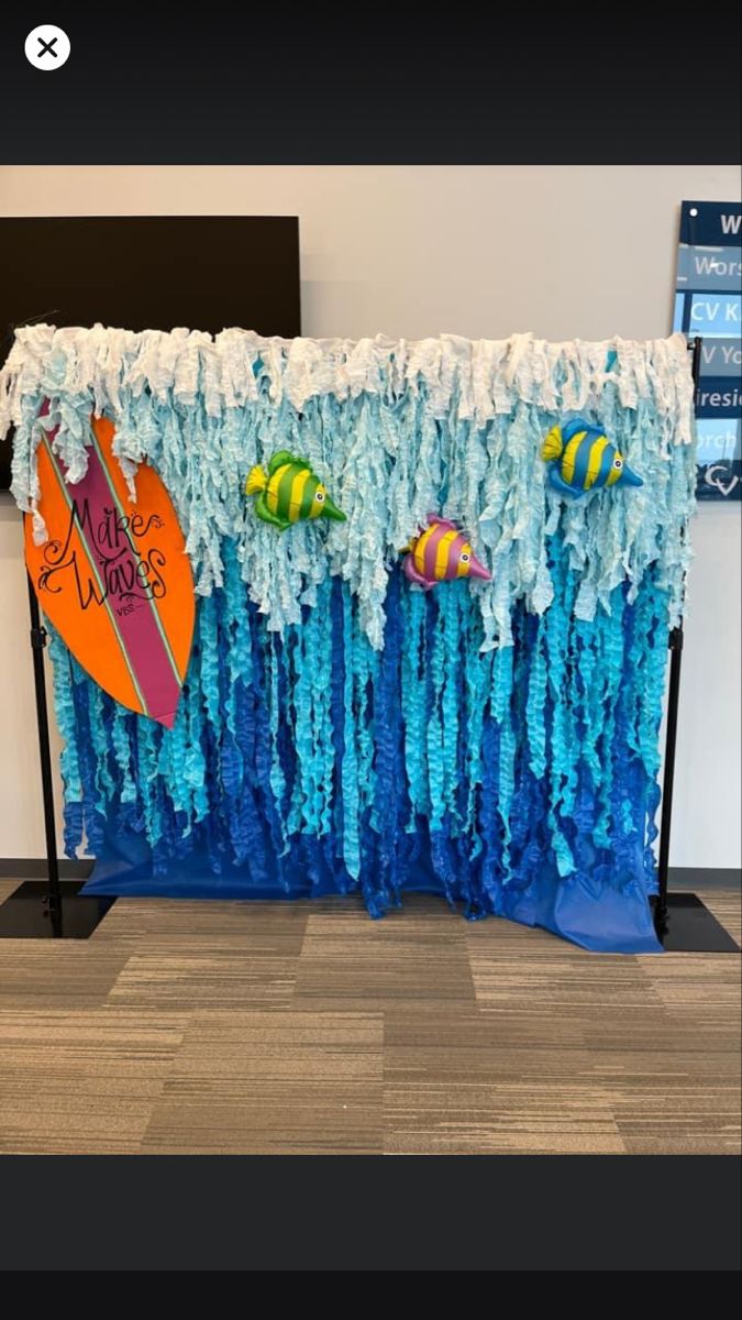 a surfboard and other items are on display in an office cubicle decorated with blue streamers