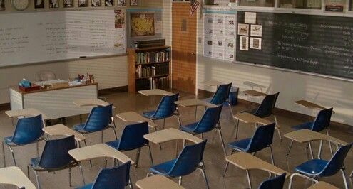 an empty classroom with desks and chairs in front of a chalkboard on the wall