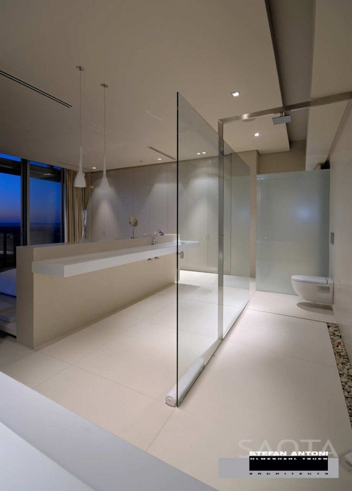 a modern bathroom with glass walls and floor to ceiling windows looking out onto the ocean