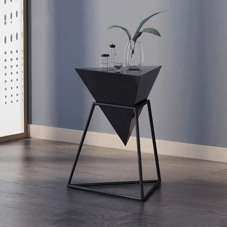 a black table with a plant on it in front of a blue wall and wooden floor