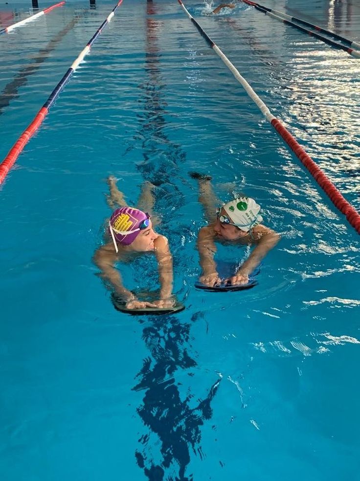 two people are in the water on their surfboards and one is wearing a helmet