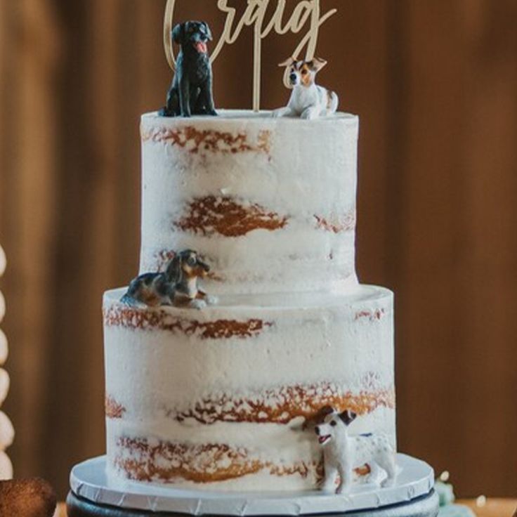 a wedding cake with two dogs on top and the word crag spelled in cursive