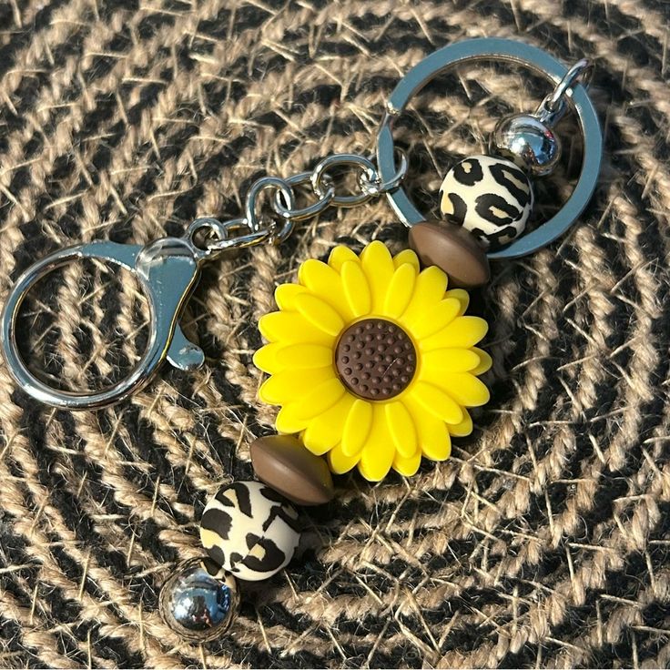 a sunflower keychain is sitting on top of a piece of woven material