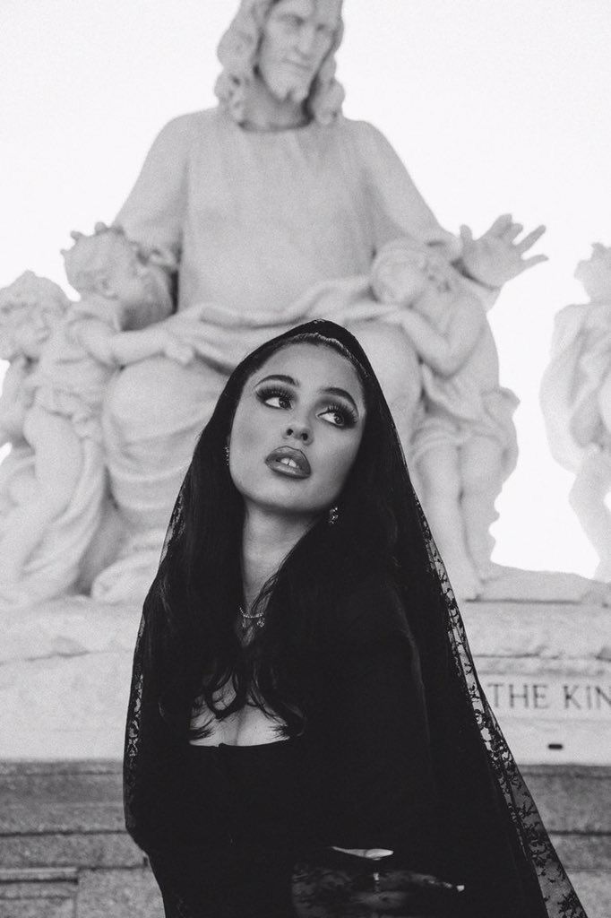 a black and white photo of a woman with long hair in front of a statue