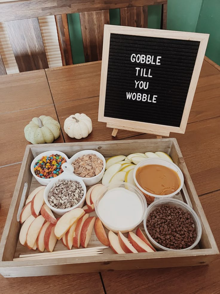 a wooden box filled with apples, cereals and condiments next to a sign that says gobble till you wobble