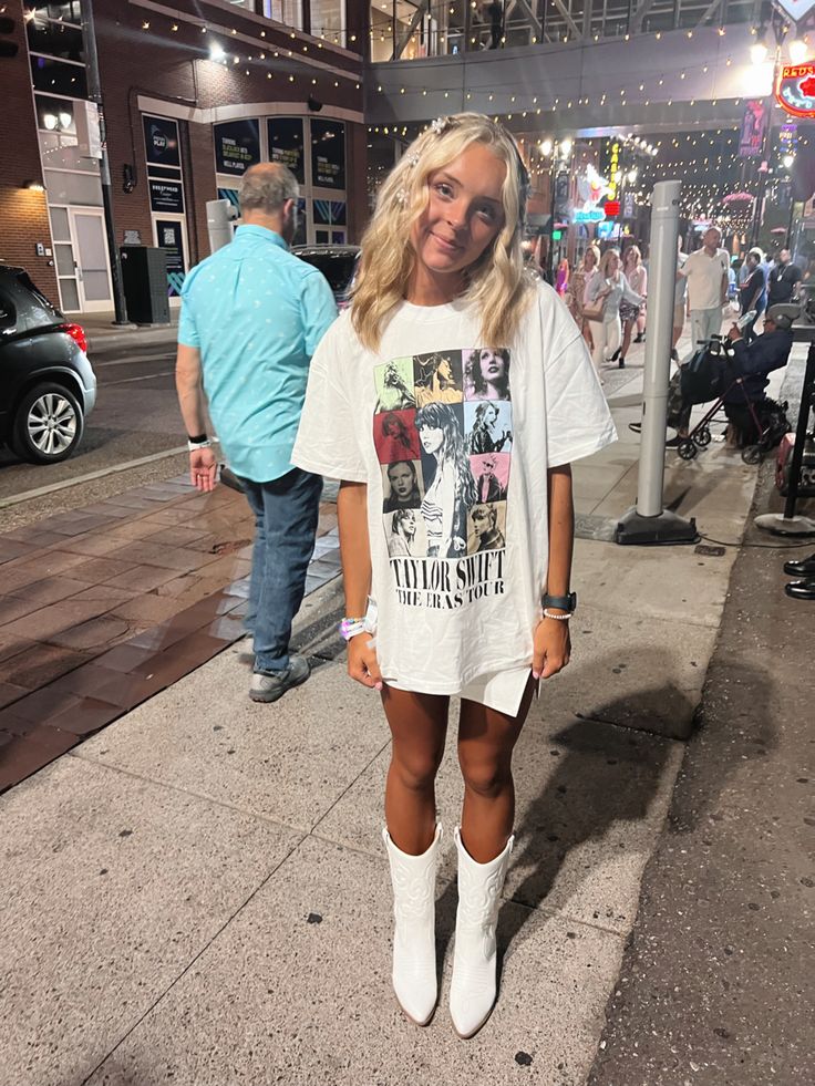 a woman standing on the sidewalk wearing white boots and a t - shirt with pictures