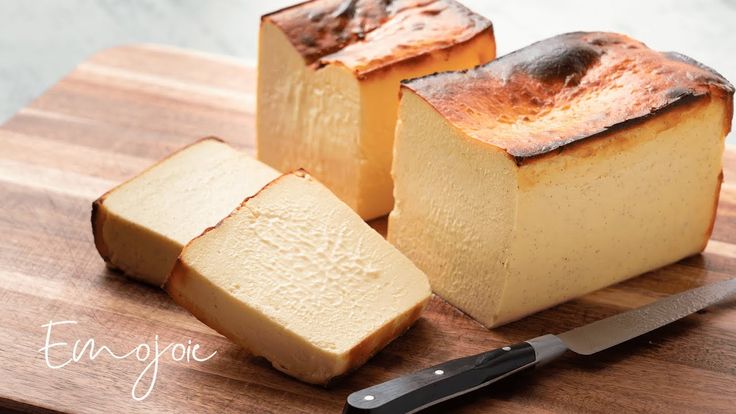 two pieces of bread sitting on top of a wooden cutting board next to a knife