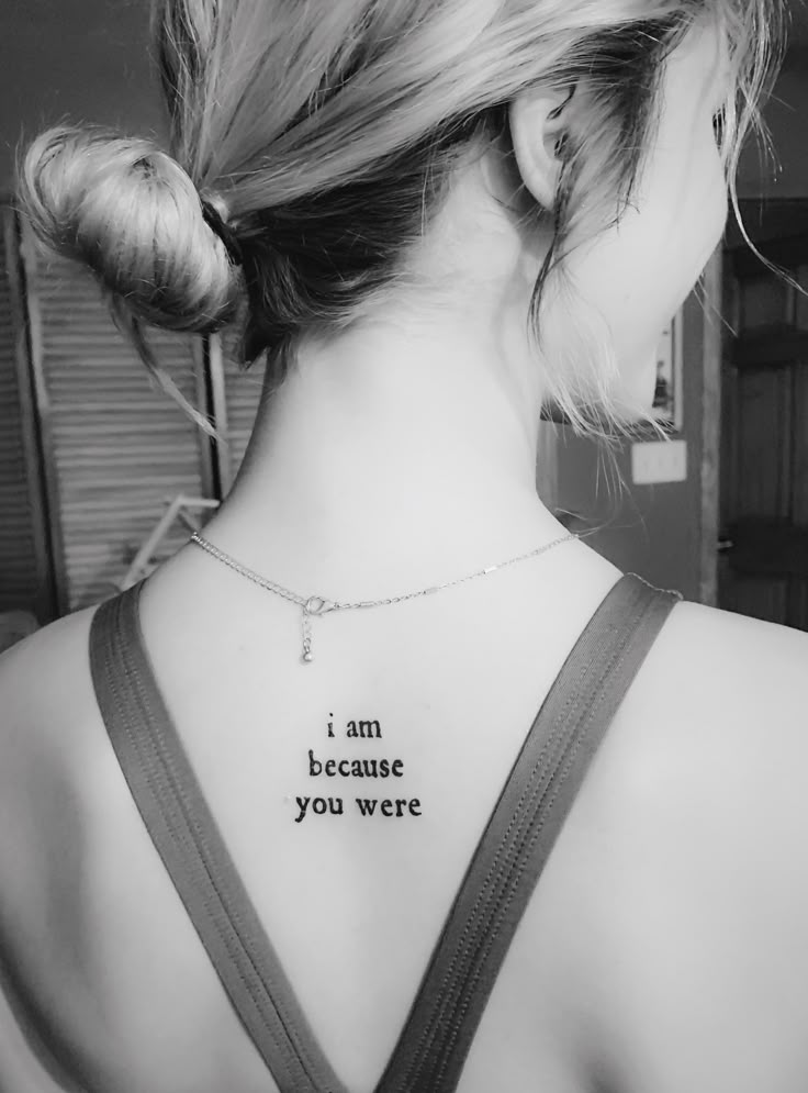 a woman with a tattoo saying i am because you were behind her back neck tattoos