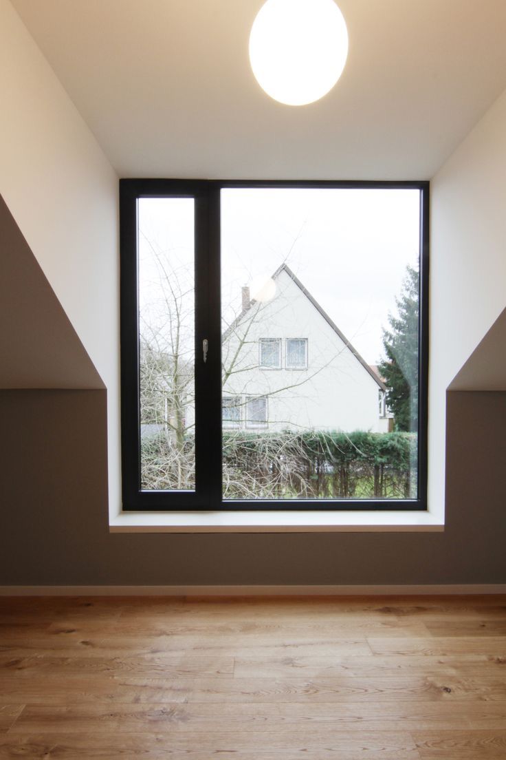 an empty room with a large window and wooden floor