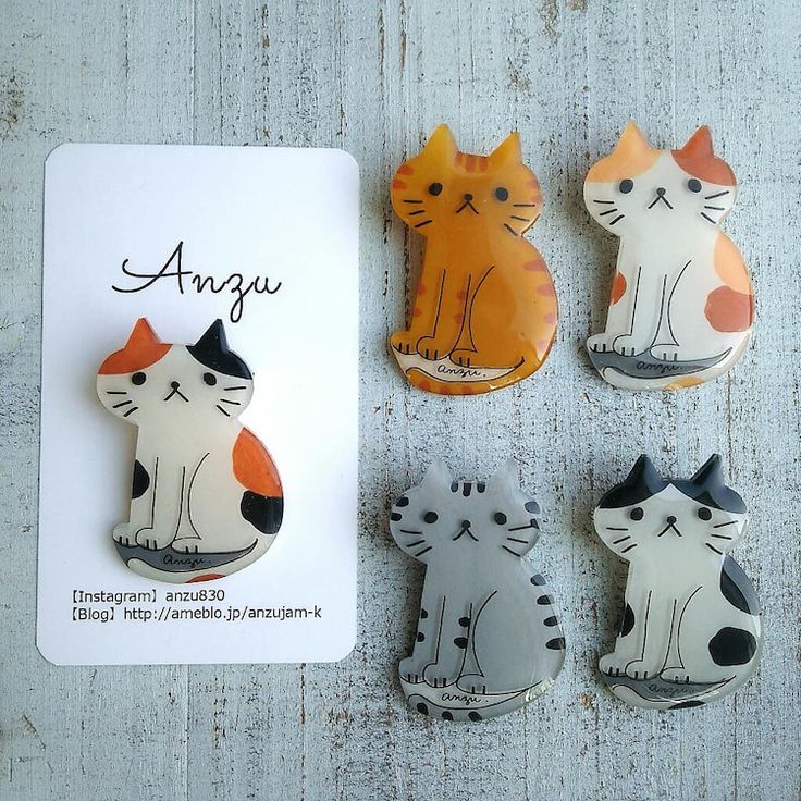 four cat magnets sitting next to each other on a white surface with an orange and black one