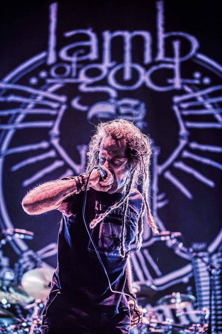 a man with dreadlocks standing in front of a microphone and drums on stage