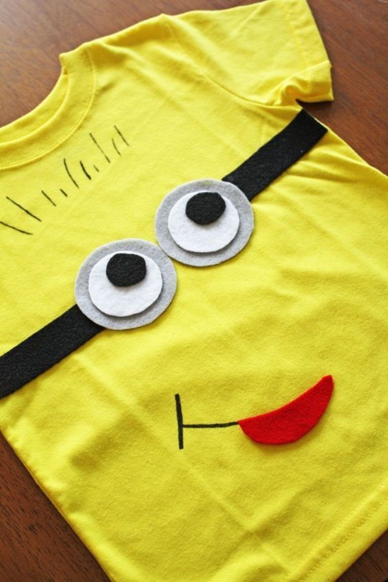 a yellow t - shirt with googly eyes on it sitting on a wooden table