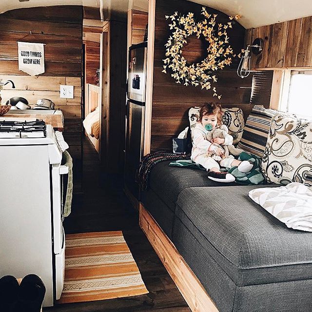 two people sitting on a couch in a small room with wood walls and flooring