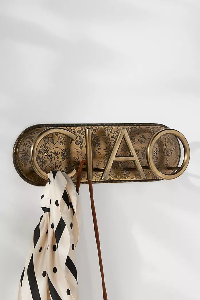 a scarf hanging on a coat rack with the word faq spelled in gold letters