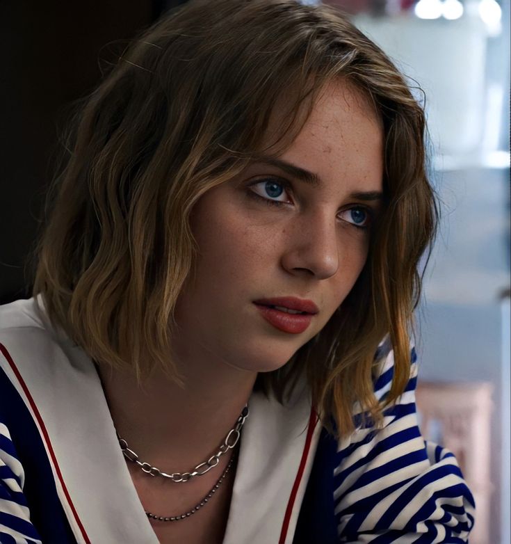 a close up of a person with a necklace on her neck and wearing a striped shirt