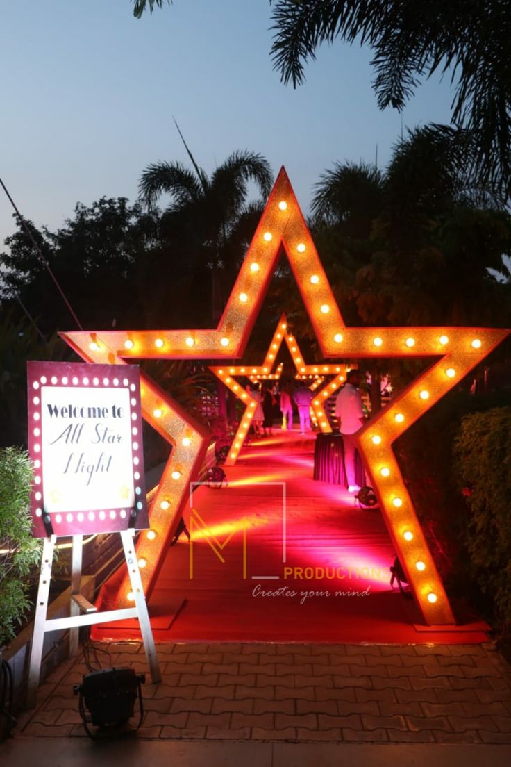 a large lighted star on the side of a road next to a sign that says welcome to all star night