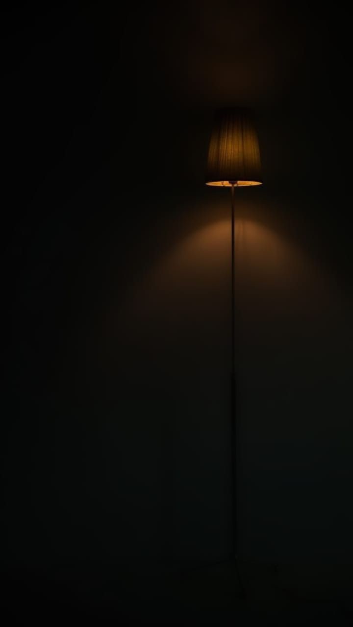 a lamp that is on in the dark with a light shining down from it's side