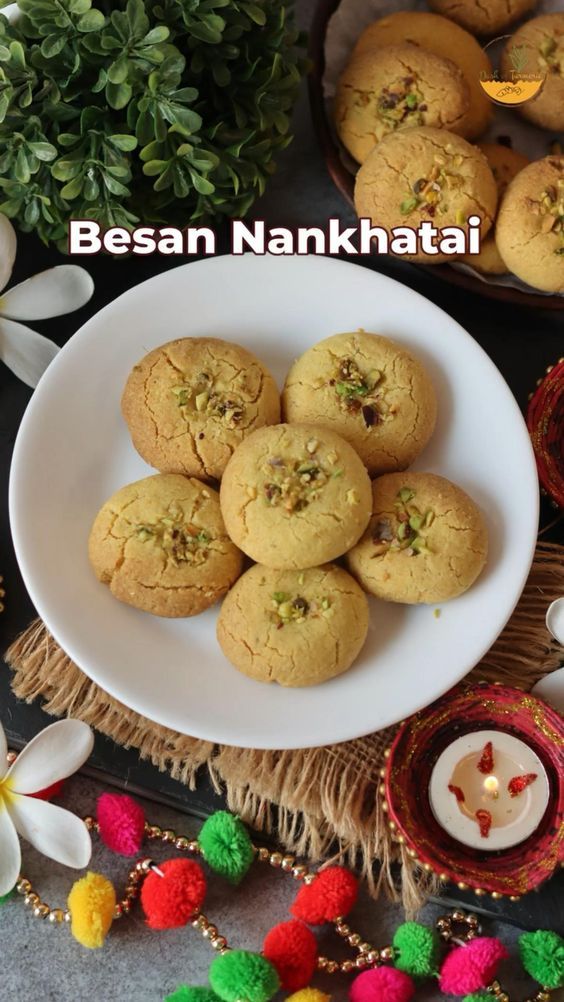 some cookies are on a white plate next to other food items and flowers with the caption besan nankhata