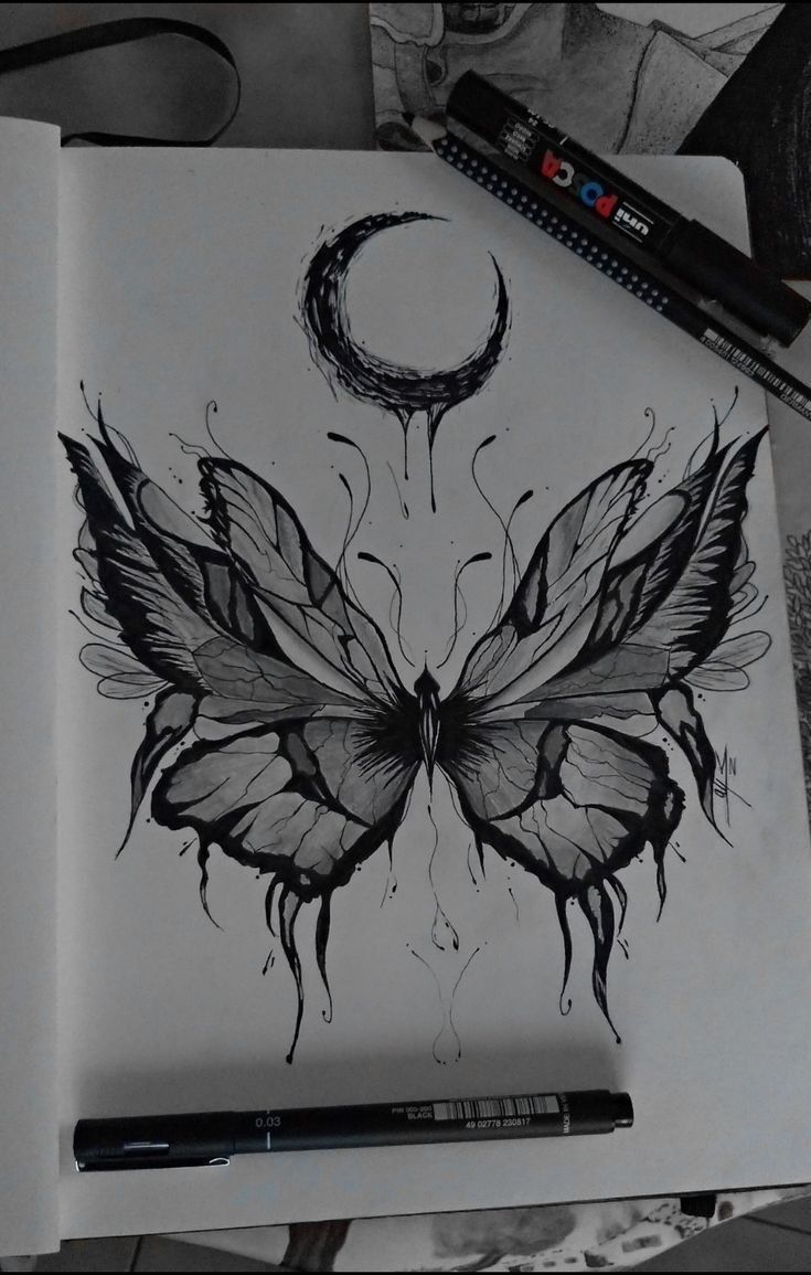 a drawing of a butterfly on paper next to a pen and ink dot marker with the moon in the background