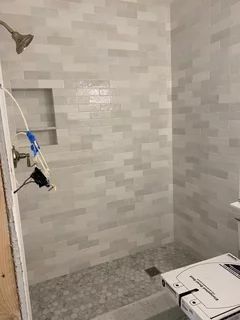 a white toilet sitting in a bathroom next to a walk in shower with tiled walls