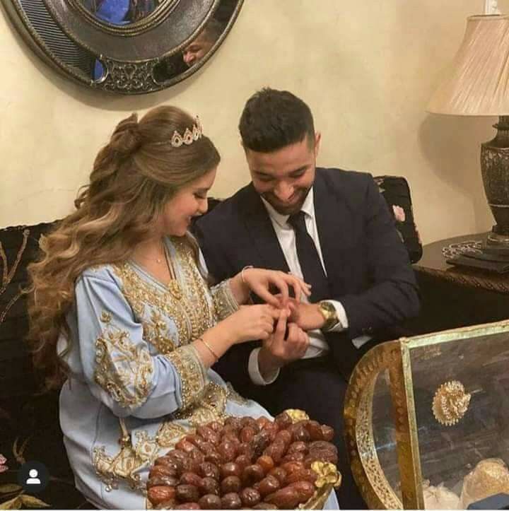 a man and woman sitting on a couch holding hands with grapes in front of them