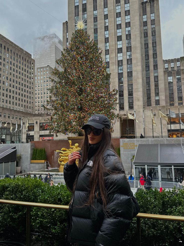 a woman is standing in front of a christmas tree and holding a piece of food