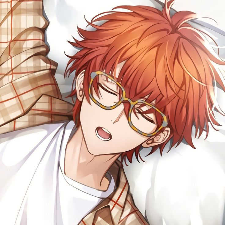 a man with red hair and glasses laying on top of a bed next to a pillow