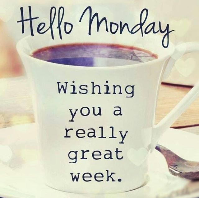 a coffee cup with the words hello monday written on it and a spoon next to it