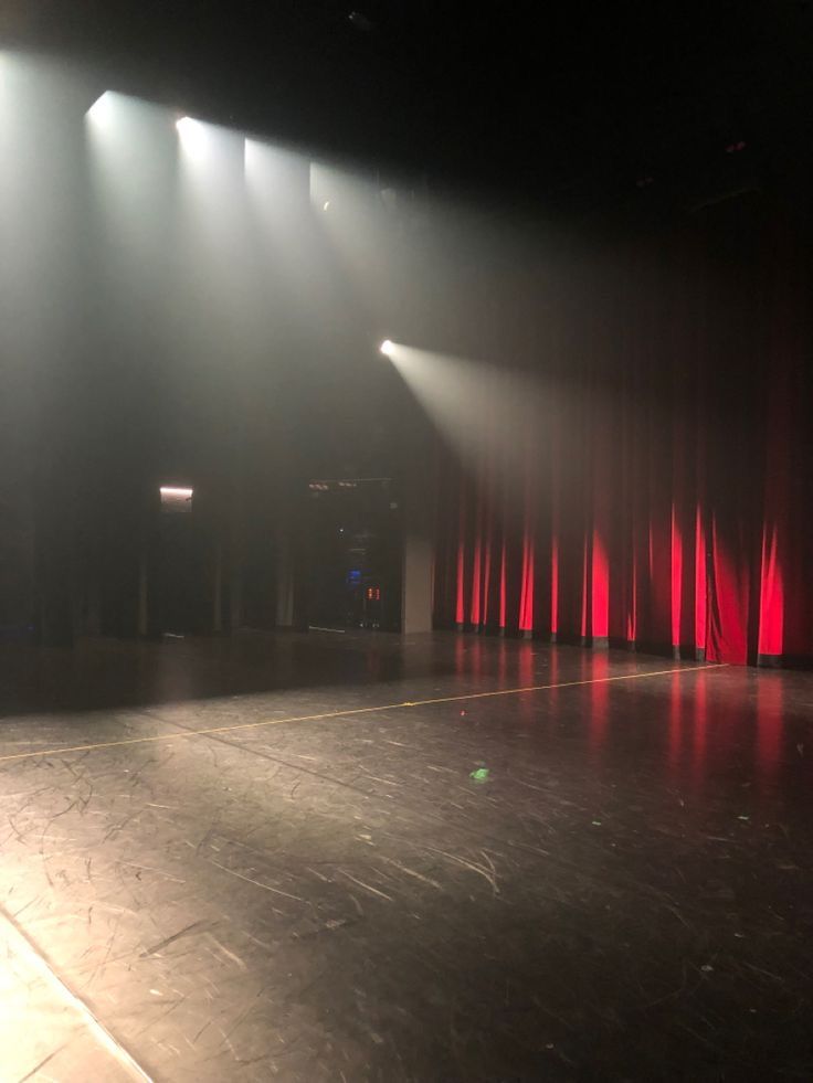 an empty stage with red curtains and spotlights