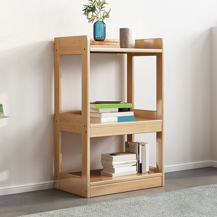 a wooden shelf with books and a vase on it next to a wall mounted plant