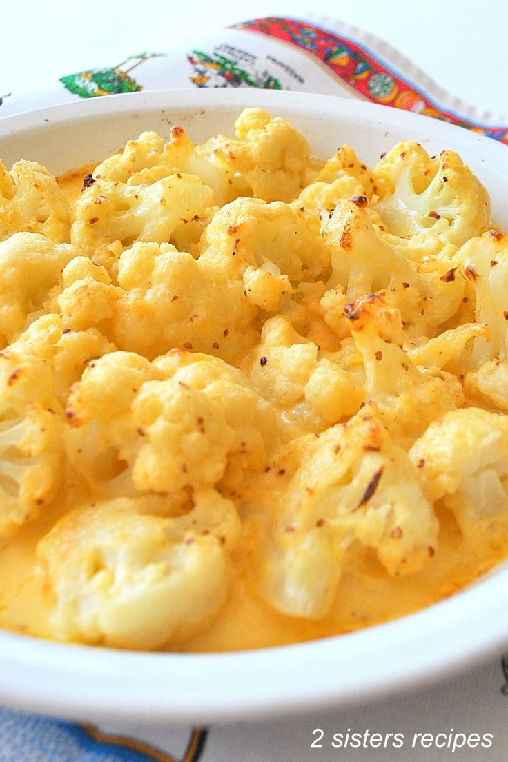 a white bowl filled with cauliflower on top of a blue and white table cloth