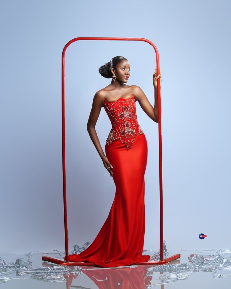 a woman in a red dress is posing for the camera with an object behind her