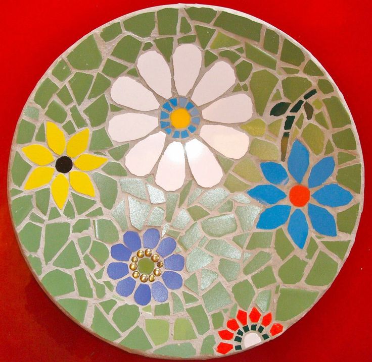 a plate with flowers painted on it sitting on a red table top next to a knife and fork