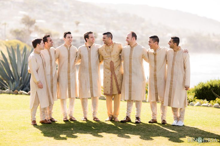 a group of men standing next to each other on top of a lush green field