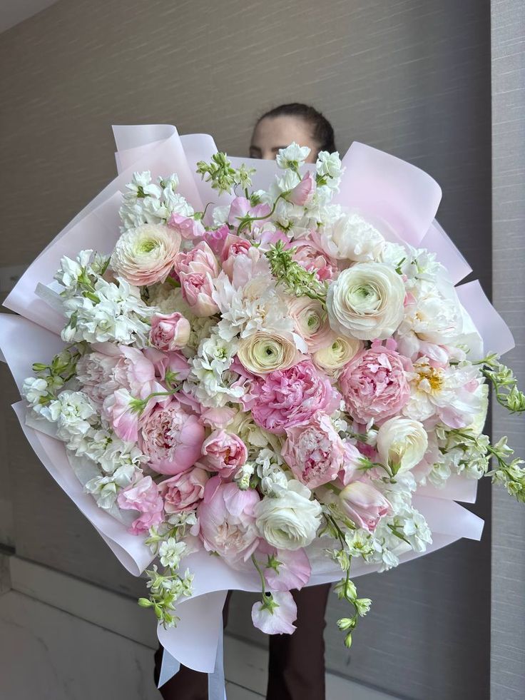 a man holding a large bouquet of pink and white flowers