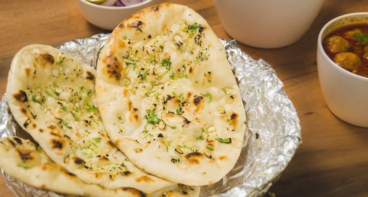 three pita breads sitting on top of tin foil next to bowls of dip