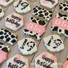 decorated cookies with black and white designs are displayed on a wooden table, along with happy birthday messages