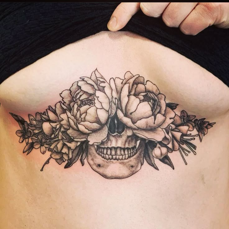 a woman's stomach with a skull and flowers on it