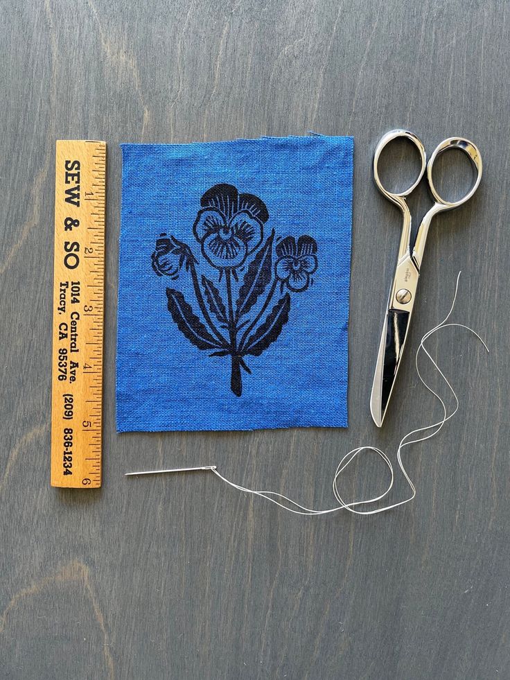 a pair of scissors sitting on top of a table next to a piece of cloth