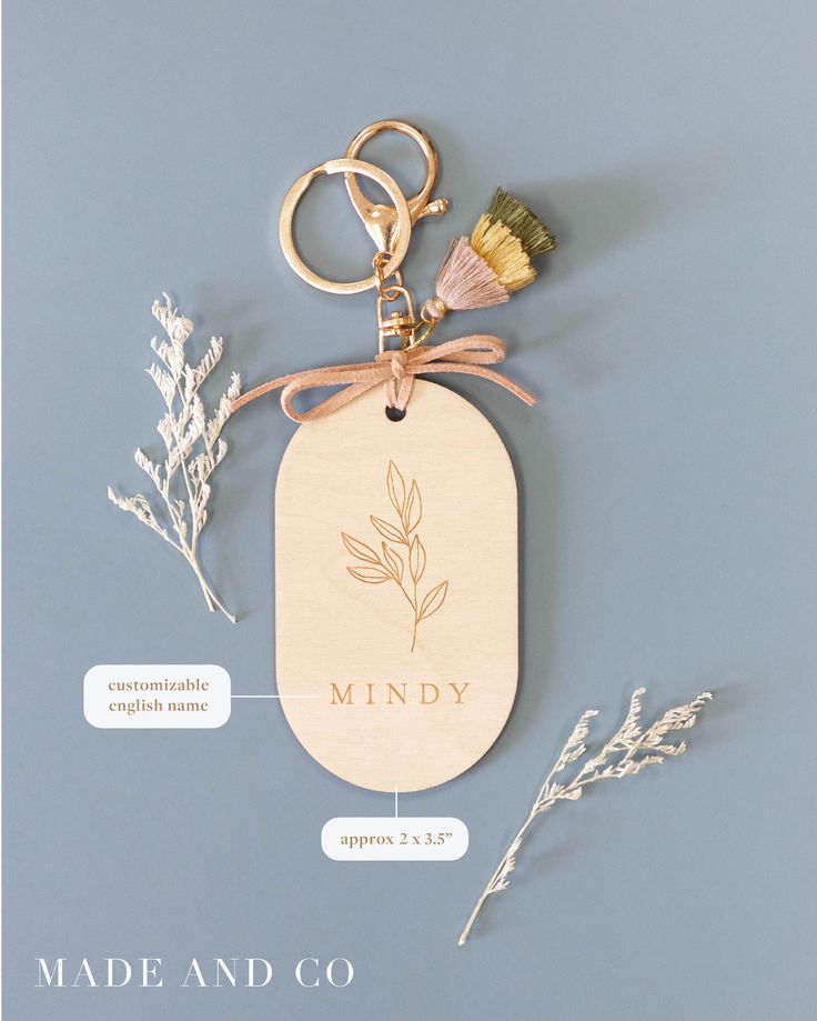 a wooden keychain with the name mindy on it and some flowers around it