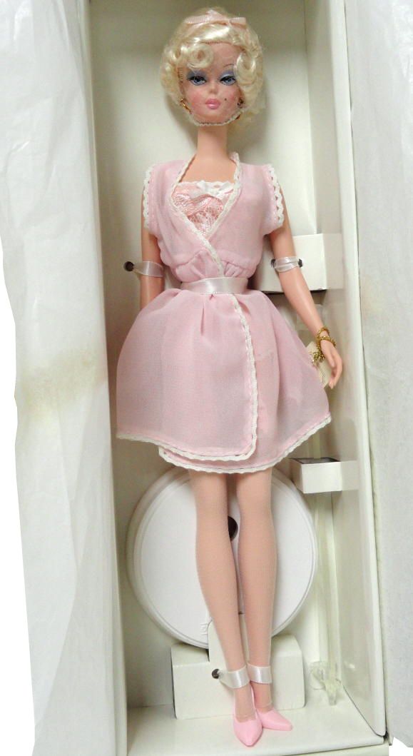 a doll in a white box with a pink dress and shoes on it's feet