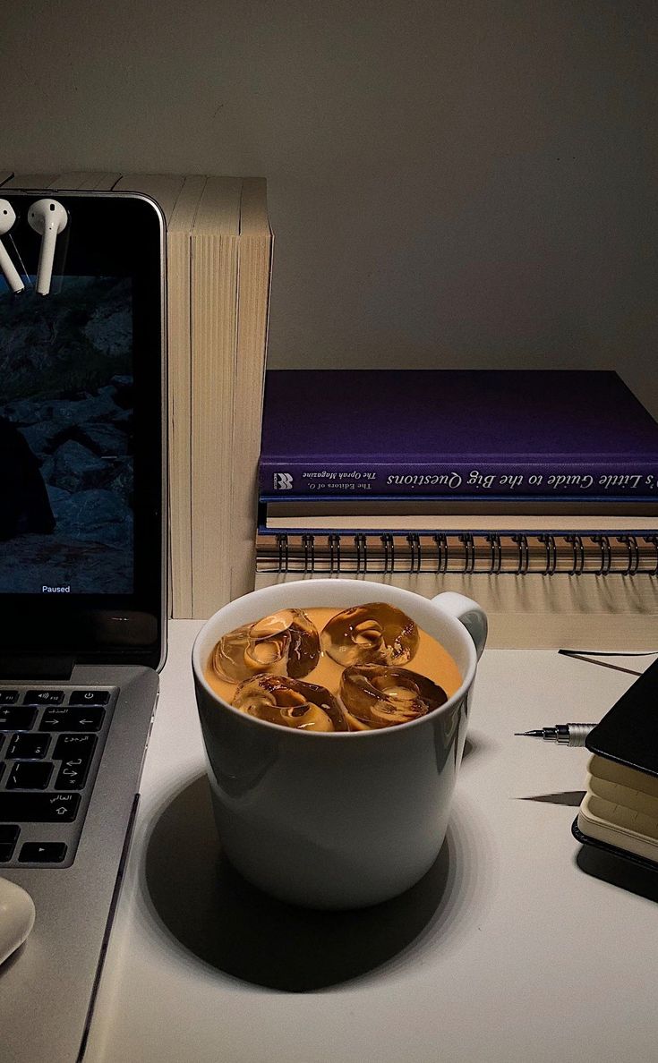 a bowl of soup sitting on top of a desk next to an open laptop computer