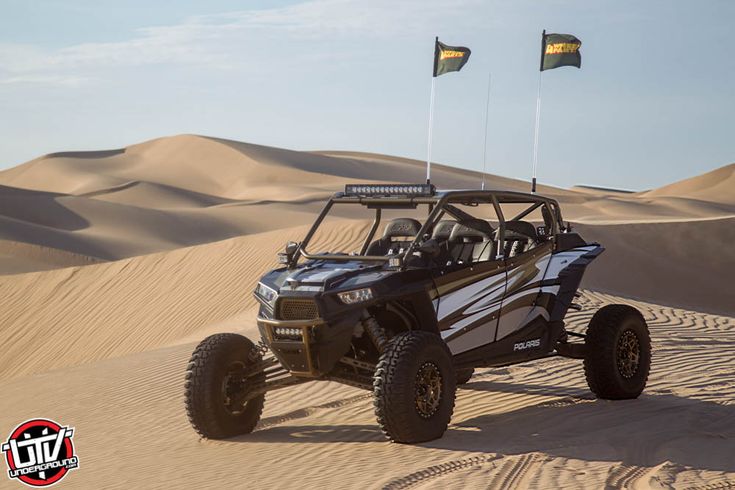 a buggy driving through the desert with two flags