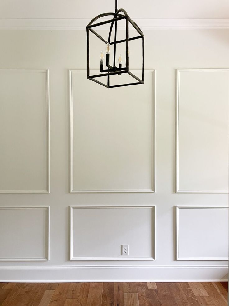 a chandelier hanging from the ceiling in a room with white walls and wood floors