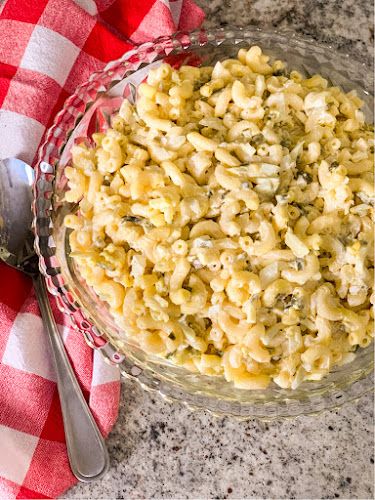 a bowl filled with macaroni and cheese on top of a red checkered napkin