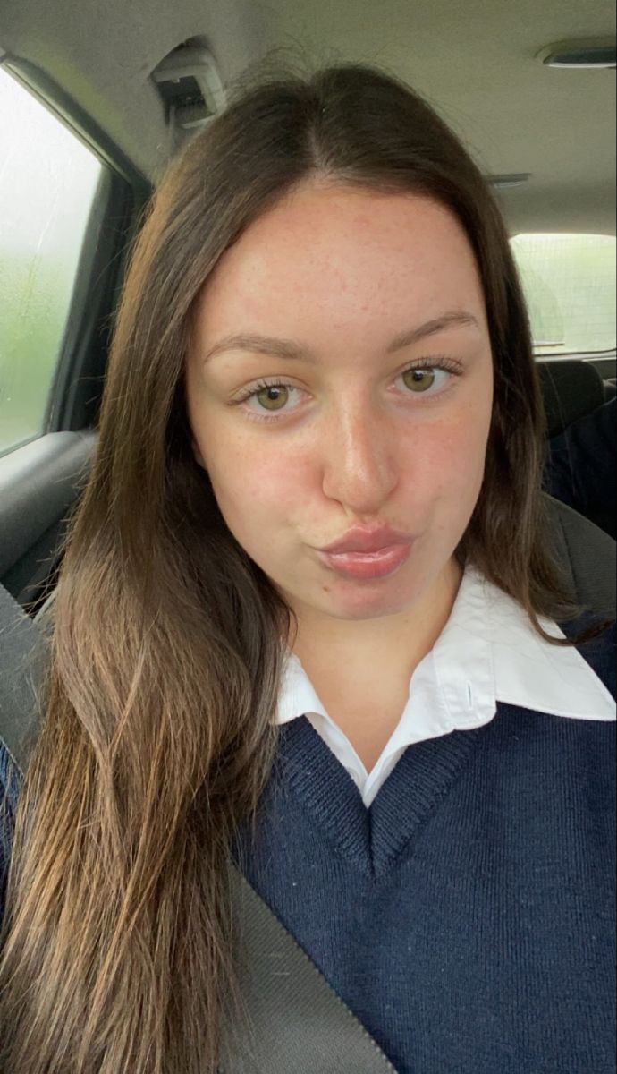 a woman with long hair sitting in the back seat of a car and making a funny face