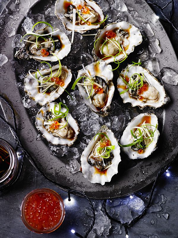 oysters on an ice tray with garnish and sauce