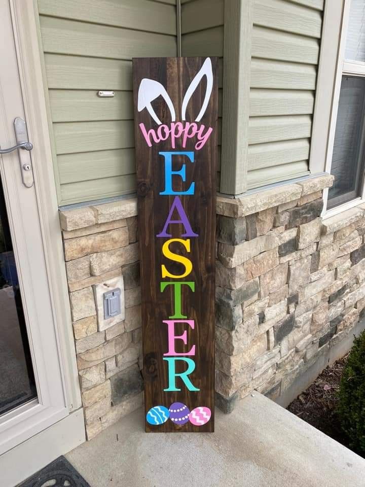 a wooden sign that says happy easter on the side of a house in front of a door